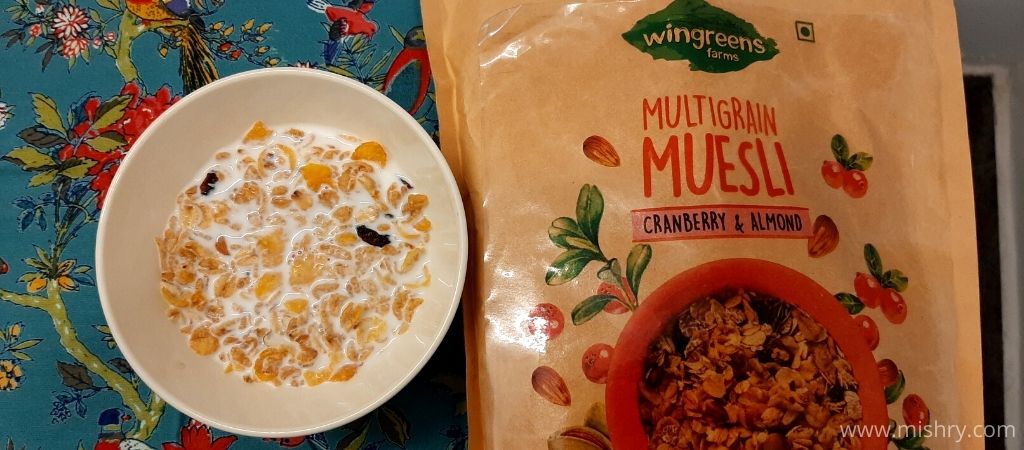 cranberry & almond wingreens farms multigrain muesli with milk served in a bowl