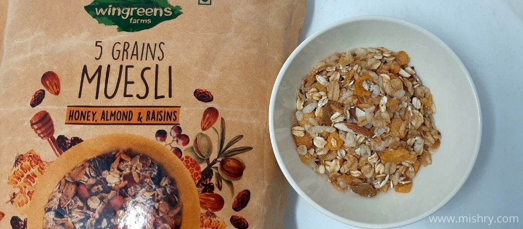 dry wingreens farms 5 grains muesli with honey, almond & raisins served in a bowl