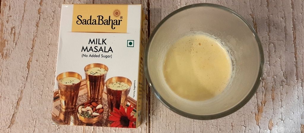 overhead look of sadabahar milk masala in a glass after mixing with hot milk