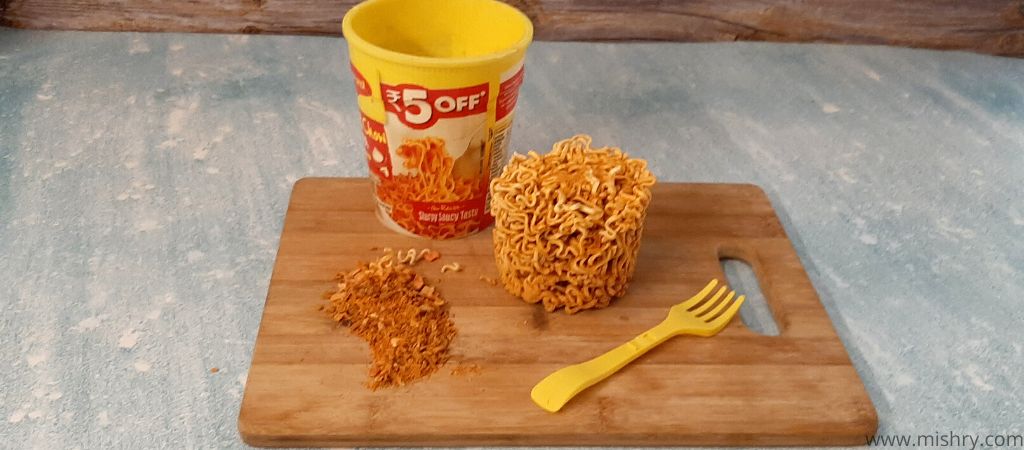unprepared noodles seasoning mix and spoon on a chopping board