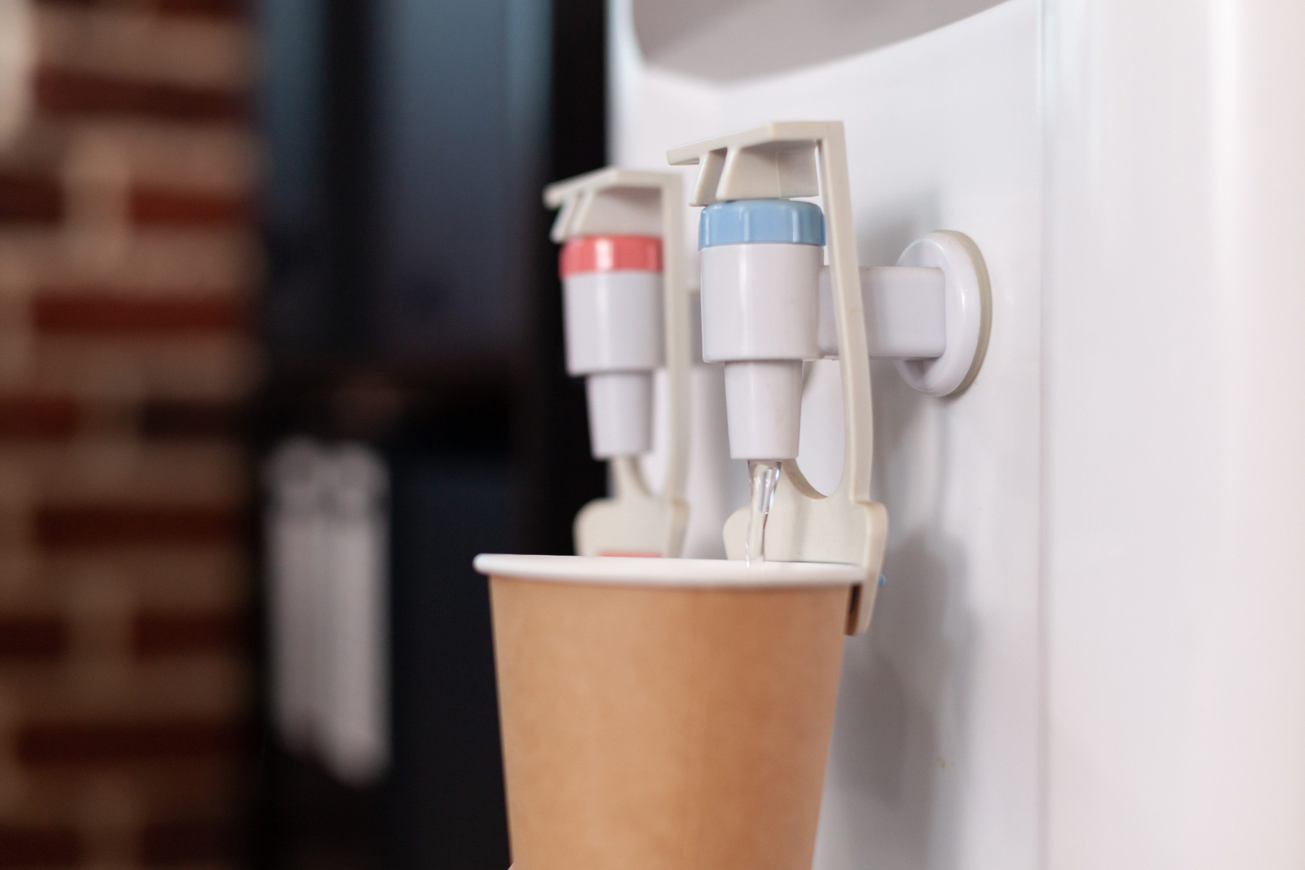Close up of disposable cup on water cooler in startup office